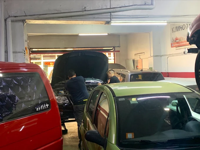 Óscar y Oier trabajando bajo el capó abierto de un coche en el taller