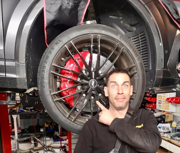 Mecánico del taller señalando una rueda con pinza de freno roja